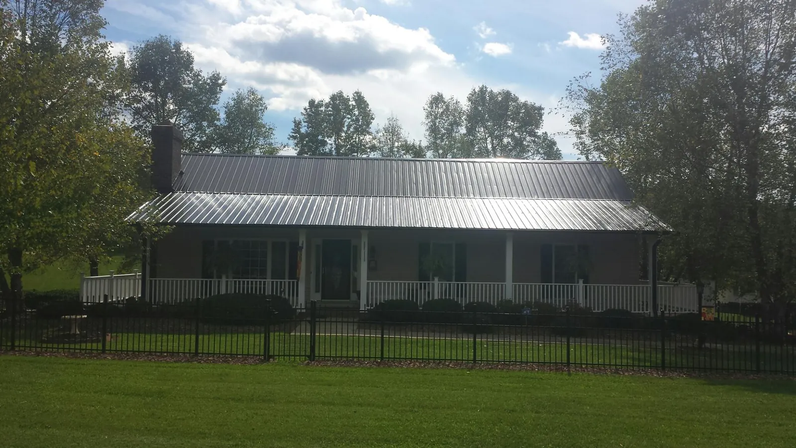 Gray metal roof on a brick ranch with a full width front porch — Gutter Guard Installation work by our crew in Nuevo