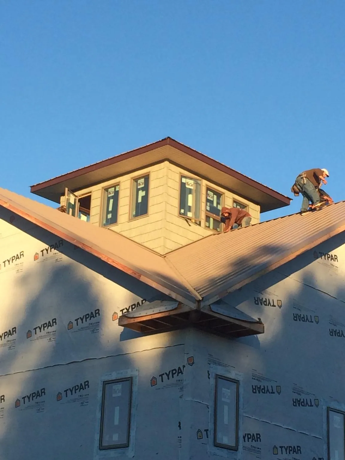 Roofers working around a rooftop cupola on a new metal roof at sunset — Roof Waterproofing in Nuevo by Roofing Brothers